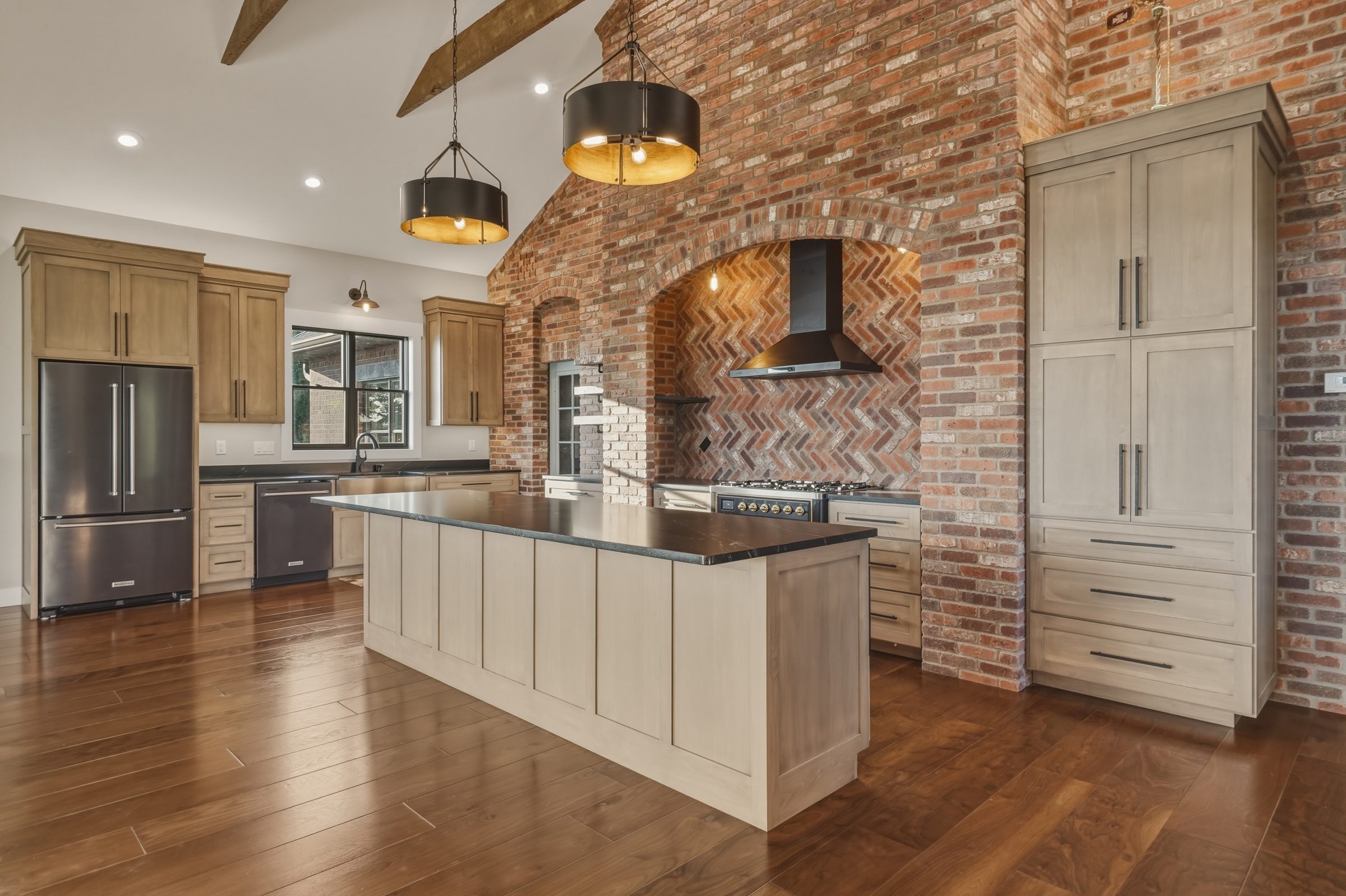 Kitchen with a brick wall, a large island and pendant lights
