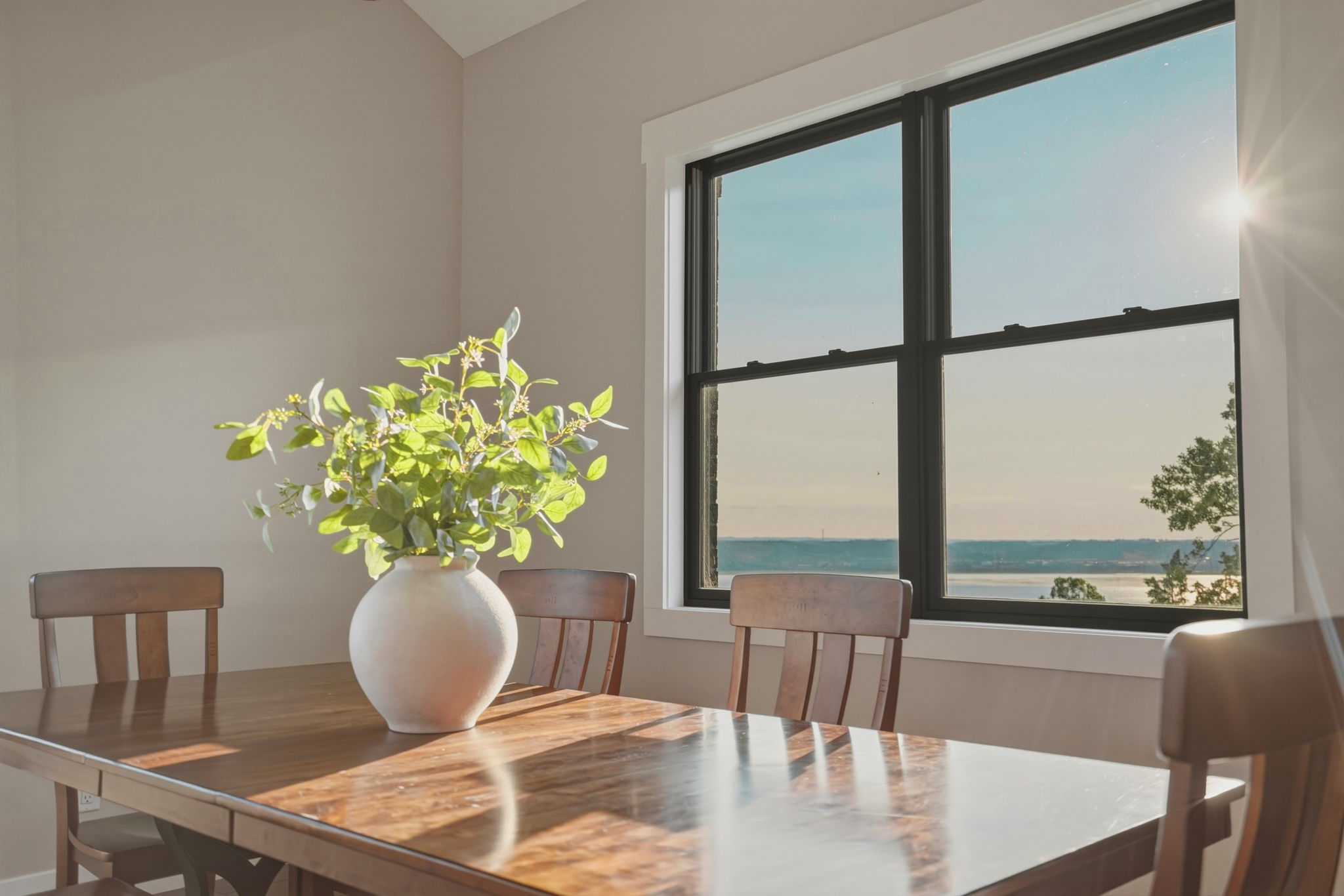 Wooden dining table with a vase of flowers beside a window