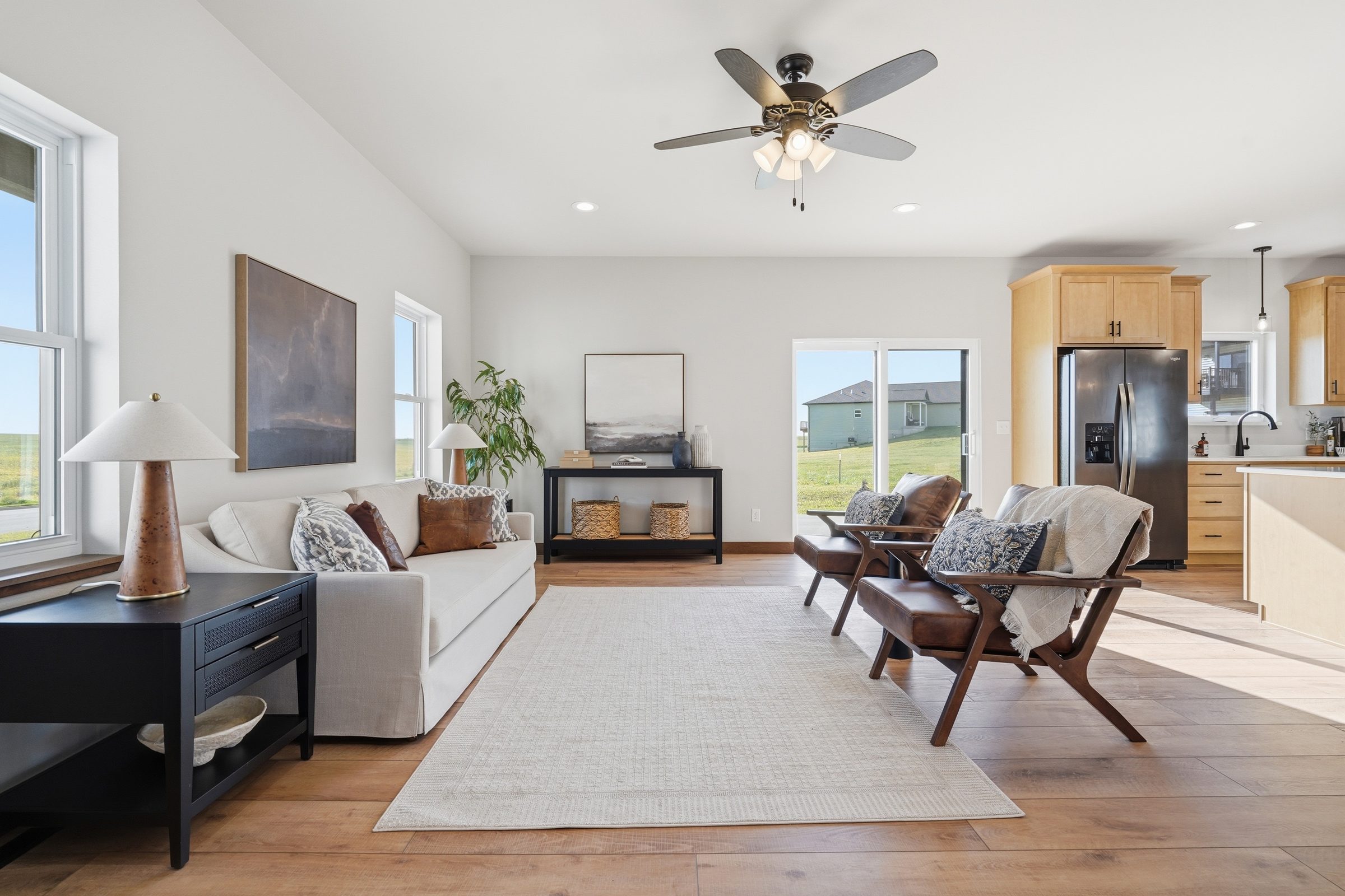 Bright open living room with a ceiling fan and the kitchen beyond